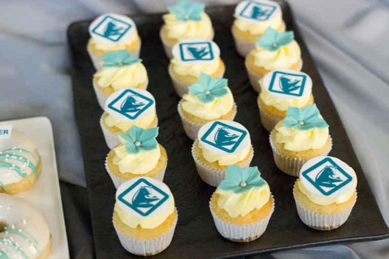 Branded mini cupcakes met logo en suikerdecoratie in huisstijl kleuren