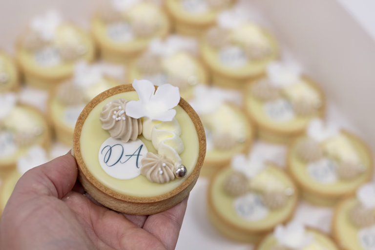 Branded chocolade tartelettes met witte details, suikerbloem en logo, in huisstijl kleuren