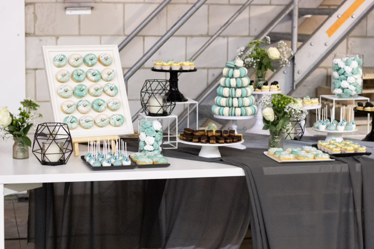 Zakelijke sweet table in zwart-turquoise- branding kleuren. Op veel gebakjes logo decoratie. Donut wall, macaron toren, branded cupcakes - prachtig gepresenteerd.