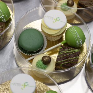 Luxe kleine relatiegeschenk - een ronde sweet box met verschillende kleine gebakjes met logo en in huisstijl kleuren.