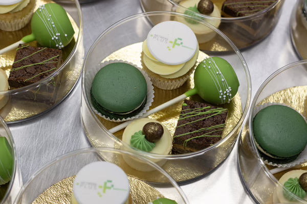 Luxe kleine relatiegeschenk - een ronde sweet box met verschillende kleine gebakjes met logo en in huisstijl kleuren.